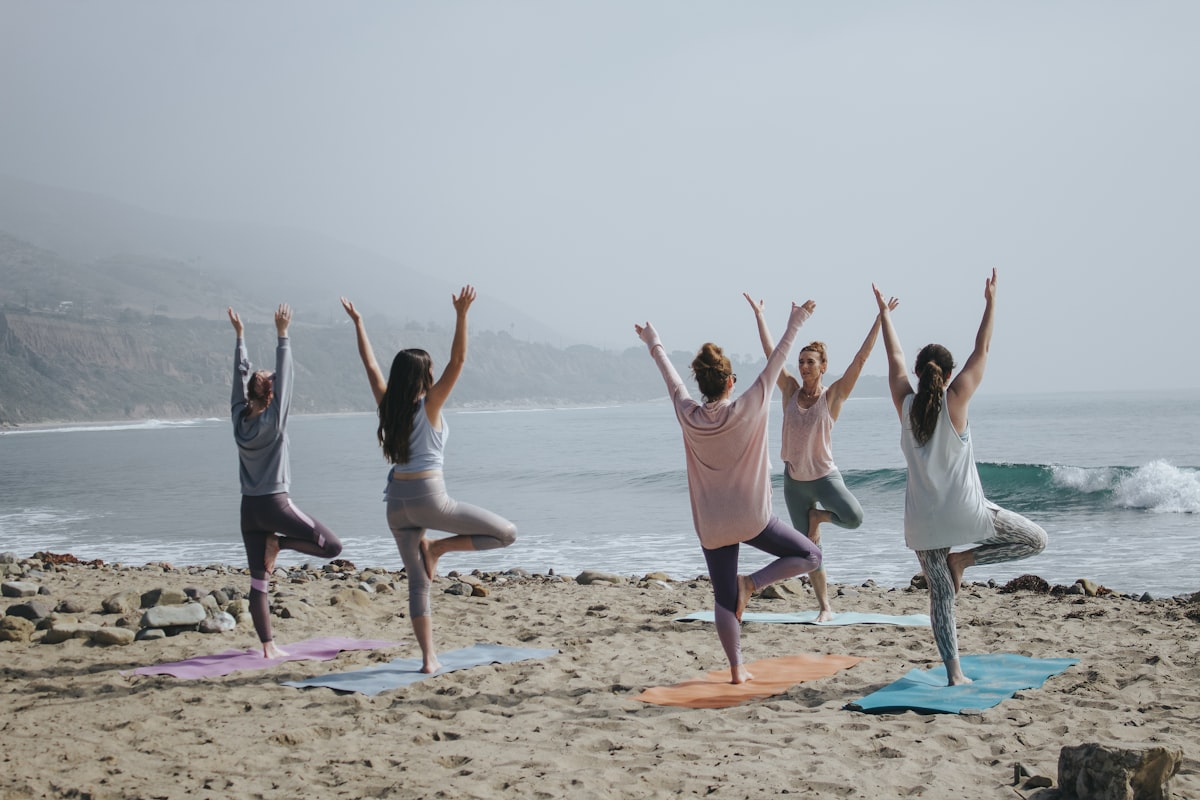 A group practicing yoga together on a sunlit beach